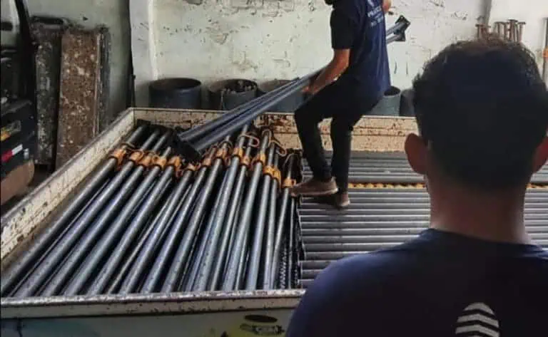 Técnicos da Prático Locações carregando escoras metálicas no caminhão para a entrega